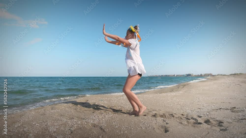 Ukrainian girl in shirt with floral wreath with multi-colored ribbons dances on coast near Black sea Ukrainian girl in shirt with floral wreath with multi-colored ribbons dances on coast near Black sea