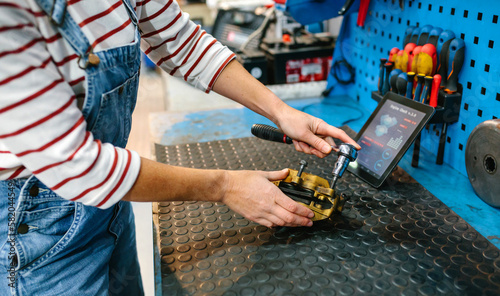 Foto Unrecognizable mechanic woman repairing caliper brake system over garage workben