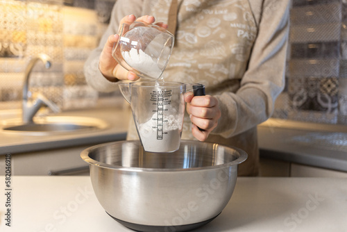 Girl, measuring flour with a measuring cup according to the recipe Process cooking food concept