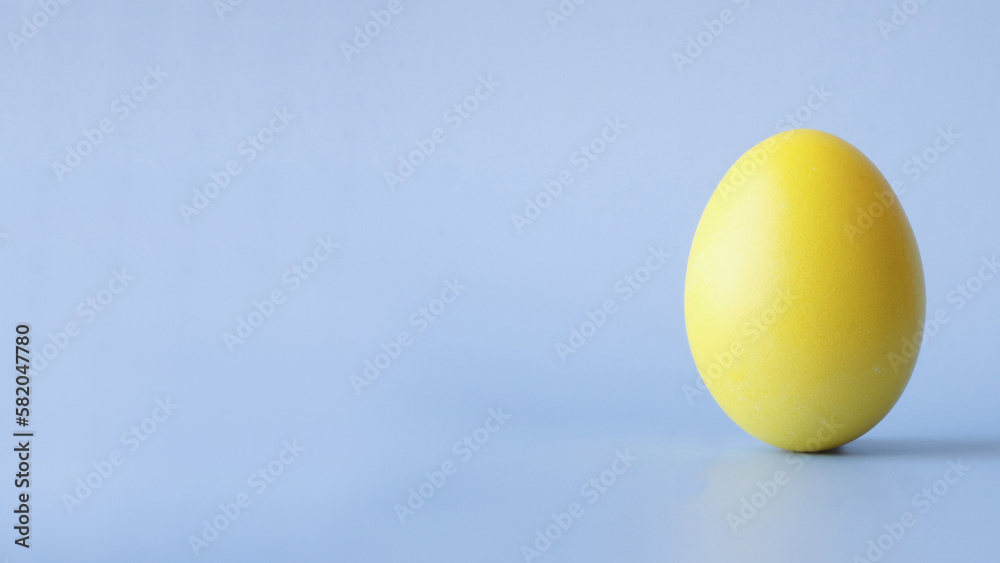 Colored yellow Easter egg on a light blue background with a place for text Colored yellow Easter egg on a light blue background with a place for text