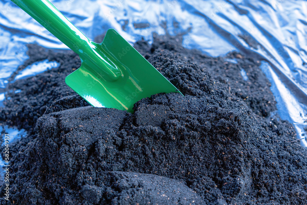 Preparation of soil mixture from fertile compost, humus and vermiculite on  black garbage bag floor in garden. Mixing the soil components for the  preparation of the substrate for transplanting plants. Stock Photo