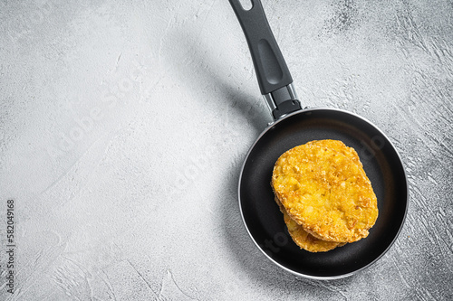 Fried Hash brown potato, hashbrown fritters in a skillet. White background. Top view. Copy space