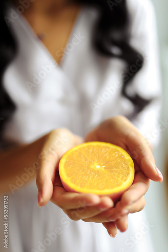 A woman holds oranges in her hands standing in a home kitchen, isolated on a white background