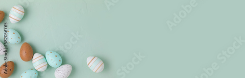 Easter frame of pastel colored eggs on light green background. Panorama, banner, flay lay, top view with copy space.