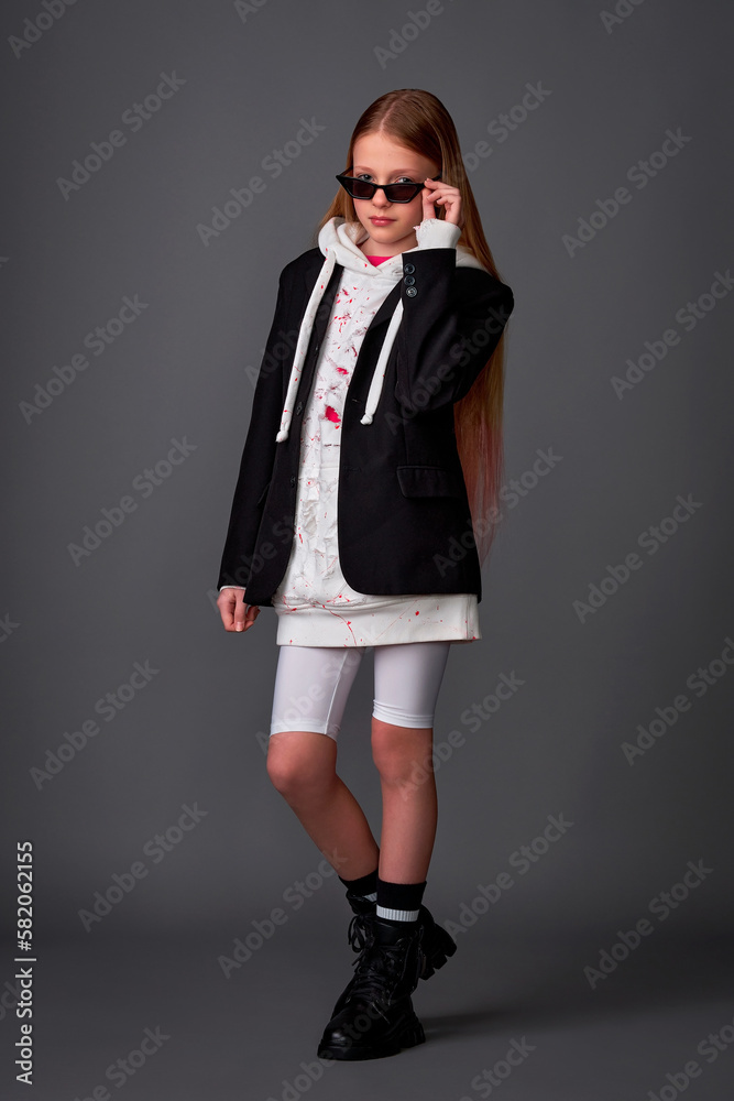Slim girl girl teenager in short leggings, top and jacket posing in the studio on a gray background Slim girl girl teenager in short leggings, top and jacket posing in the studio on a gray background