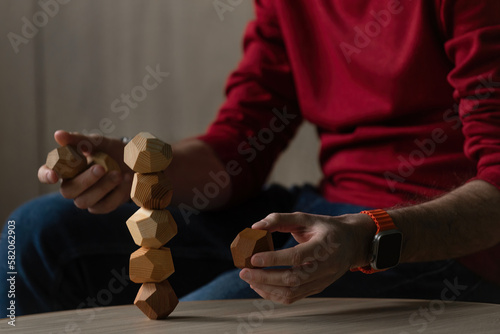 Male hands put together different figures from wooden polyhedrons, eco games for adults and children, antistress toys made of natural wood photo