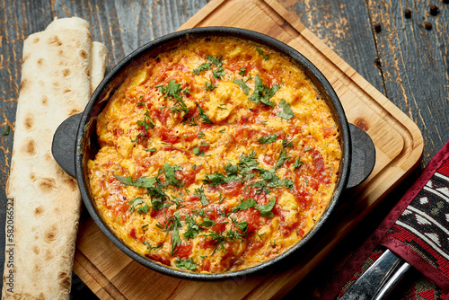 Menemen with eggs, tomato, green peppers, and spices served with bread in pan. Turkish breakfast photo