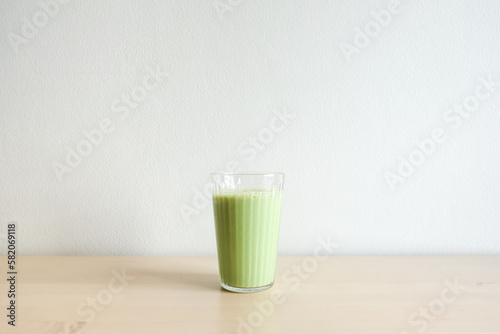 Homemade iced green matcha tea and milk in glass on wooden table.