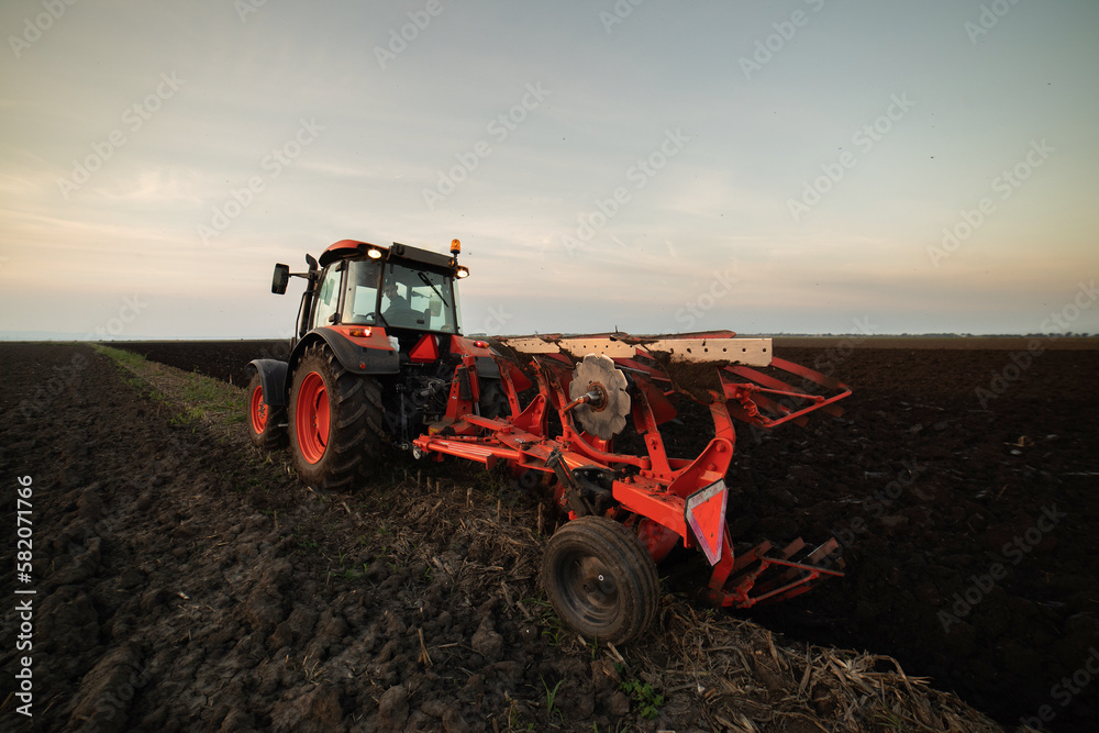Obraz premium Tractor on the field during sunset.