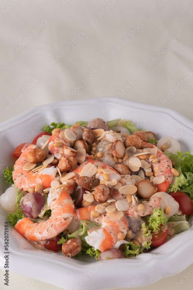 chilled cold big prawn salad with mixed fresh fruit in sesame sauce and garlic nuts in plate on wood table asian chinese halal food banquet menu for restaurant