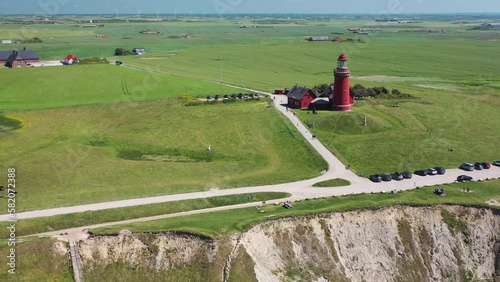 View of red lighthouse Bovbjerg Fyr and the cliffs at the danish coast. Fly away drone fligth from lighthouse. Aerial view of landscape Danish North Sea coast, Jutland, Denmark, Europe.
 photo