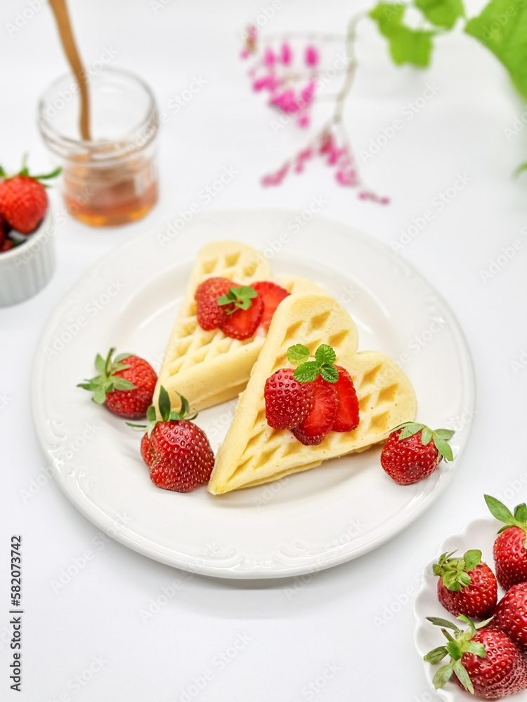 Selective focus of Waffles garnished with strawberries on a white plate with white background Selective focus of Waffles garnished with strawberries on a white plate with white background