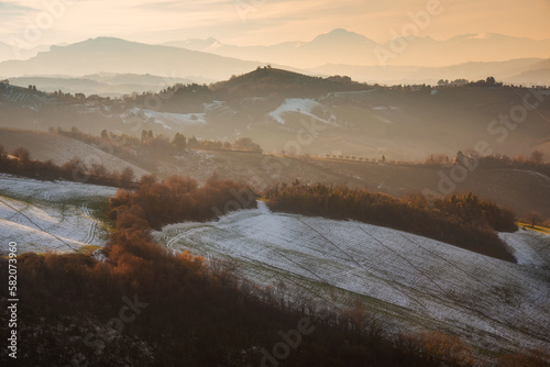 Countryside landscape inwinter with snow, agricultural fields among hills photo