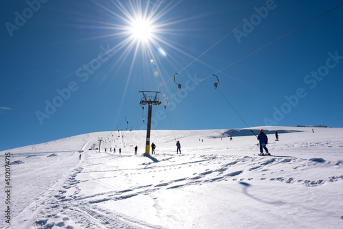 People using ski lift on sunny winter day on ski resort