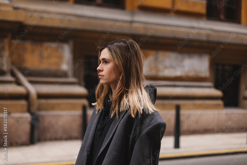 Fototapeta premium Photo of cute charming young woman wear grey jacket, calm walking outside city street. Girl look at side.