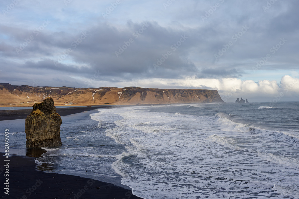 Plage de VIk en Islande, prise par drone donnant sur les falaises et un rocher immergé 