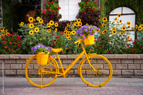 Yellow bicycle with flowers in a garden