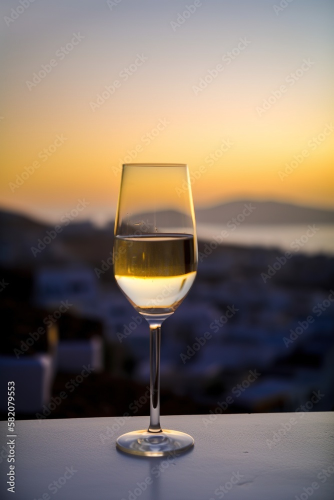 Glass of white wine on balcony with sunset view over Mediterranean island, AI generative