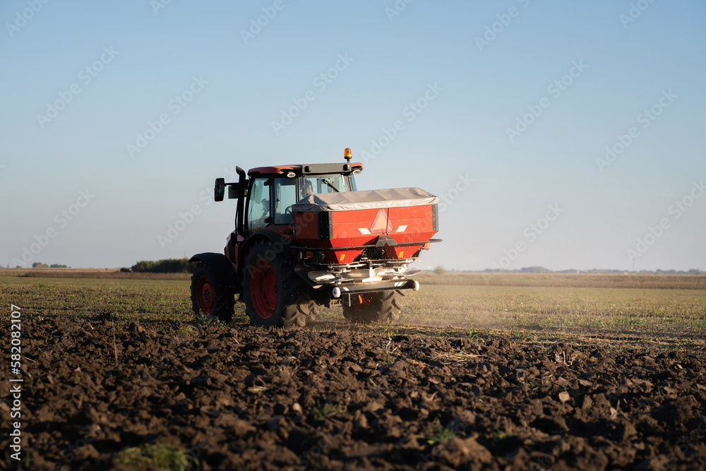 Tractor spreading artificial fertilizers in field Tractor spreading artificial fertilizers in field