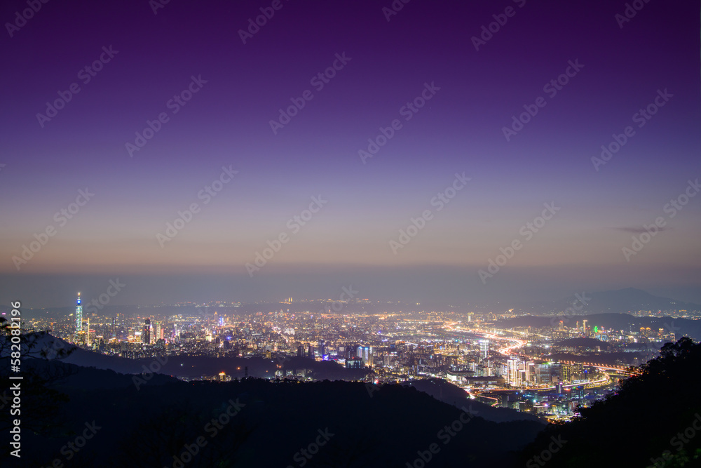 Fantasy orange sky. The vibrant and bustling night scene of Taipei City. Night view of the city surrounded by mountains is hazy and dreamy. Dajianshan, Taiwan