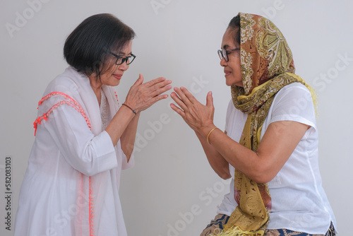 Two women in white greeting each other. photo