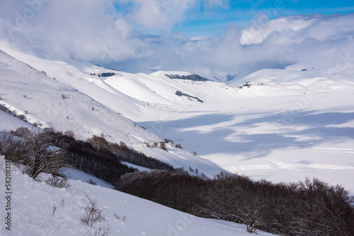 Winter landscape, valley and hills covered with snow on bright sunny day