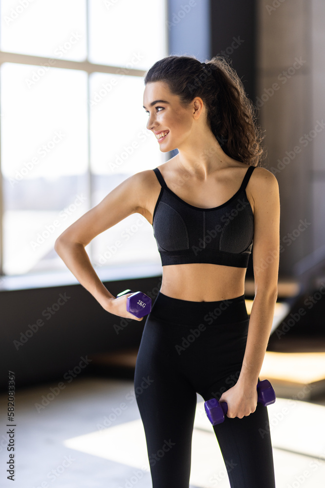 Determined woman losing weight at home and exercising with dumbbells. Determined woman losing weight at home and exercising with dumbbells.