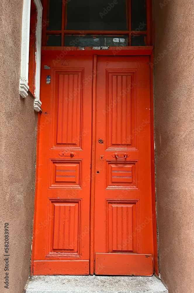 Old orange wooden door in a grey wall