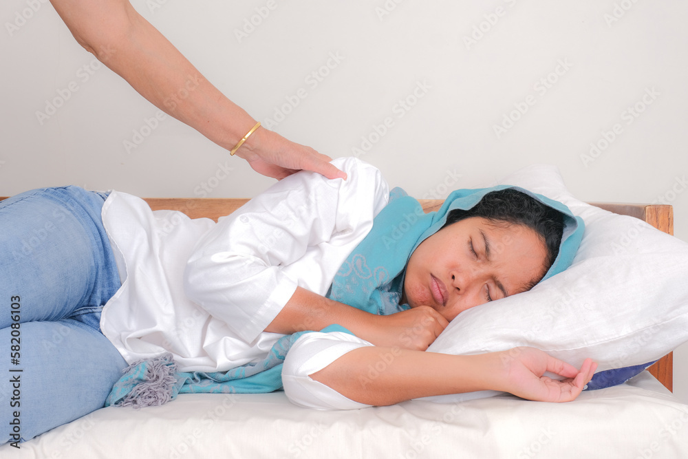 A young woman was sleeping soundly and a hand shook her shoulder to wake her up. A young woman was sleeping soundly and a hand shook her shoulder to wake her up.
