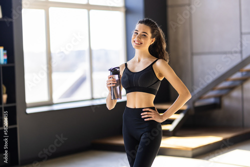 Portrait of young fitness woman drinking water after a workout at home. © F8  \ Suport Ukraine