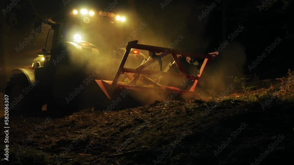 Forest mulcher processes tree remains after bark beetle infestation at night. Follow shot