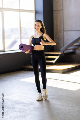 Athletic fitness woman with yoga mat indoors. Exercise at home.