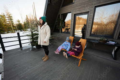 Mother with two daughters on terrace off grid tiny house in the mountains.