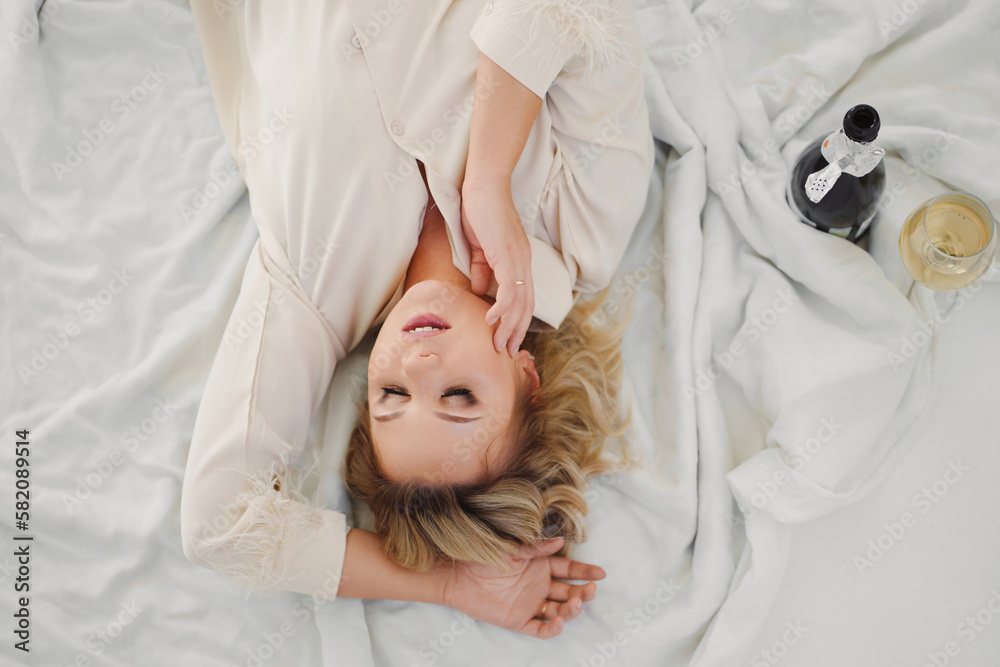 top view. blonde in delicate pajamas in bed with a champagne top view. blonde in delicate pajamas in bed with a champagne