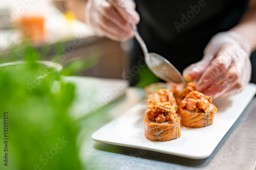 Fototapeta Naklejka Na Ścianę i Meble -  professional chef's hands making sushi roll in a restaurant kitchen
