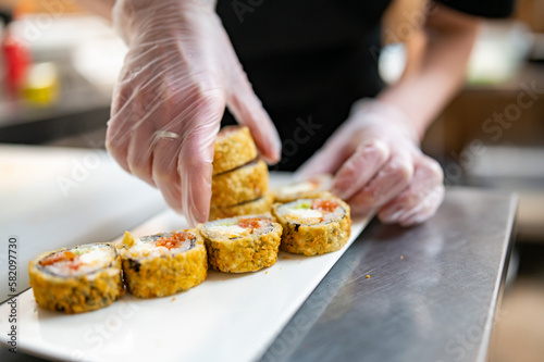 professional chef's hands making sushi roll in a restaurant kitchen