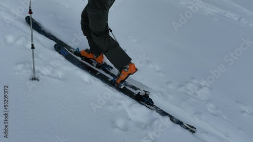 Aerial Ski touring man crossing over the camera view in the mountains in winter season fresh snow. Ski touring on skin uphill in a line. Powder day. ski vacation travel concept. 