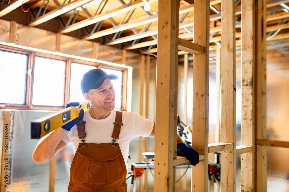 Worker using nail gun to build basement room Worker using nail gun to build basement room