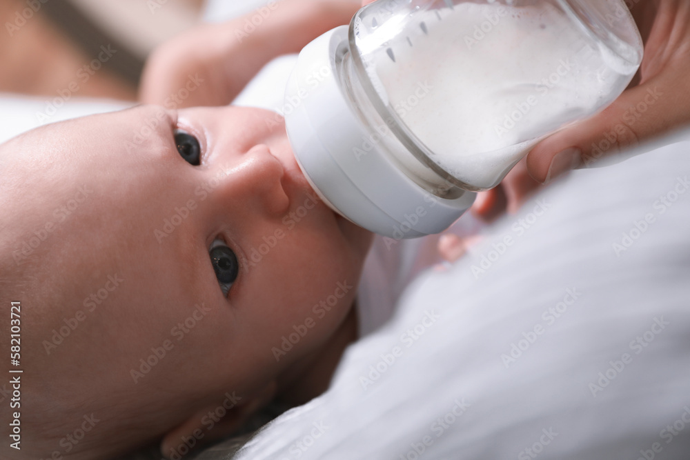 Mother feeding her little baby from bottle, closeup