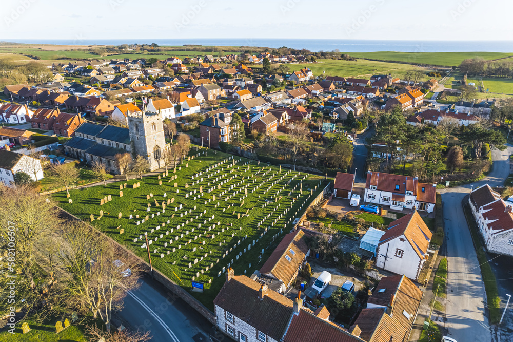 drone shot of a cemetery surrounded by small houses in Flamborough, United Kingdom. High quality photo