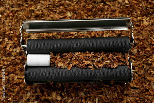 Roller with filter and tobacco, closeup view. Making hand rolled cigarette