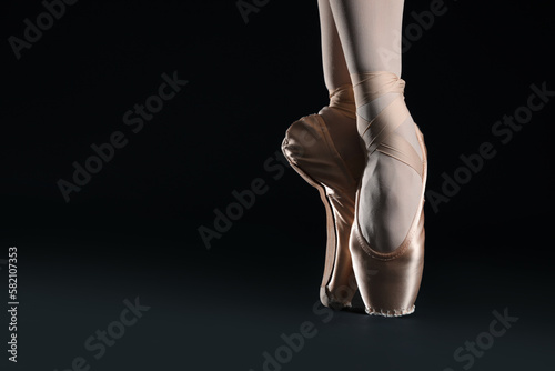 Ballerina in pointe shoes dancing on black background, closeup. Space for text © New Africa