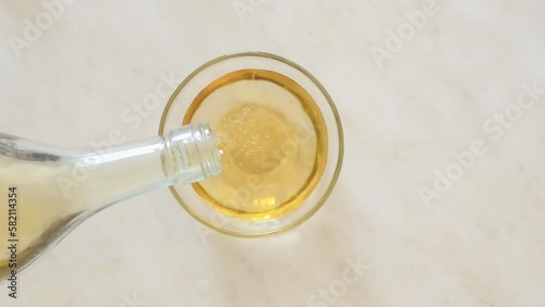 apple cider vinegar is poured from the bottle into a glass bowl.