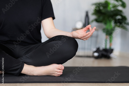 yoga and meditation concept - close up of woman doing yoga sitting in lotus pose on yoga mat
