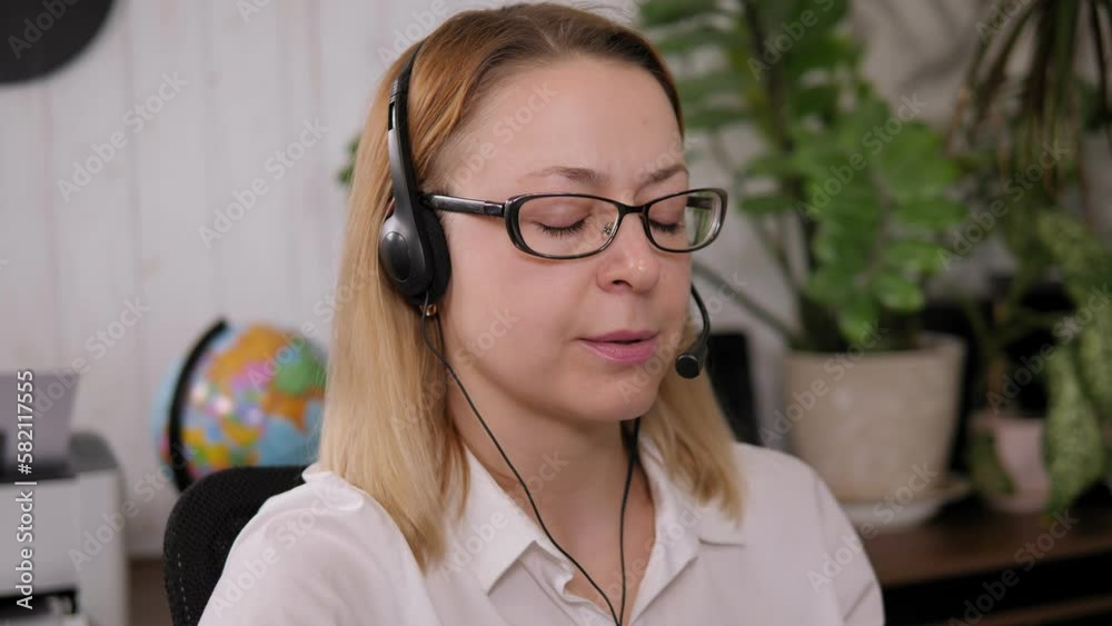 Smiling woman working as customer support operator with headset in a call center. Portrait of happy sales agent sitting at desk and looking at camera. Customer care support service representative. Smiling woman working as customer support operator with headset in a call center. Portrait of happy sales agent sitting at desk and looking at camera. Customer care support service representative.