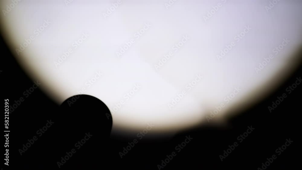 Unrecognizable Person Shines a Flashlight on the Wall in a Dark Room. Close-up. Silhouette of a pocket flashlight illuminates the wall in the dark. Spot or beam of light from a lantern. Shadow. 4K.