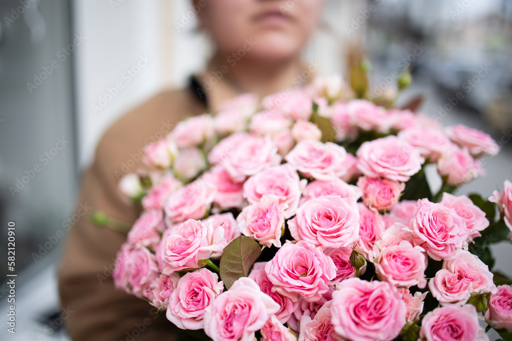 Bouquet of roses in the hands of a woman there is no face on the street in the afternoon of spring.Close up bouquet of pink small roses woman with no face. Flower delivery, birthday, mothers day, Bouquet of roses in the hands of a woman there is no face on the street in the afternoon of spring.Close up bouquet of pink small roses woman with no face. Flower delivery, birthday, mothers day,