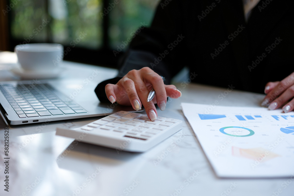 Woman accountant use calculator and computer with holding pen on