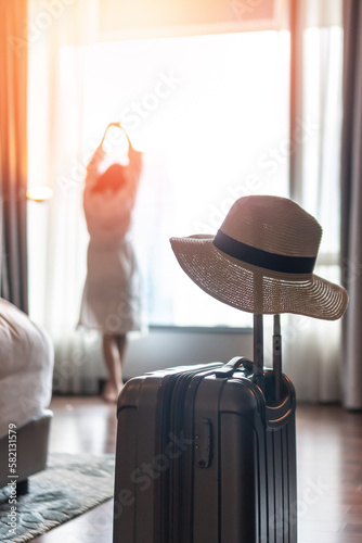 Fotografie Traveller woman with luggage in business hotel guest room looking out toward cit