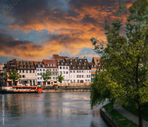 Strasbourgs Rustic River Cityscape at Sunset with beautiful ill river and boats - majestic timbered Alsatian houses in background - red sunset